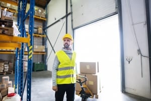 Male warehouse worker pulling a pallet truck.