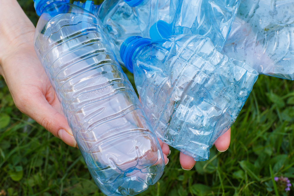 Plastic bottles of mineral water in hand of woman, concept of littering of environment