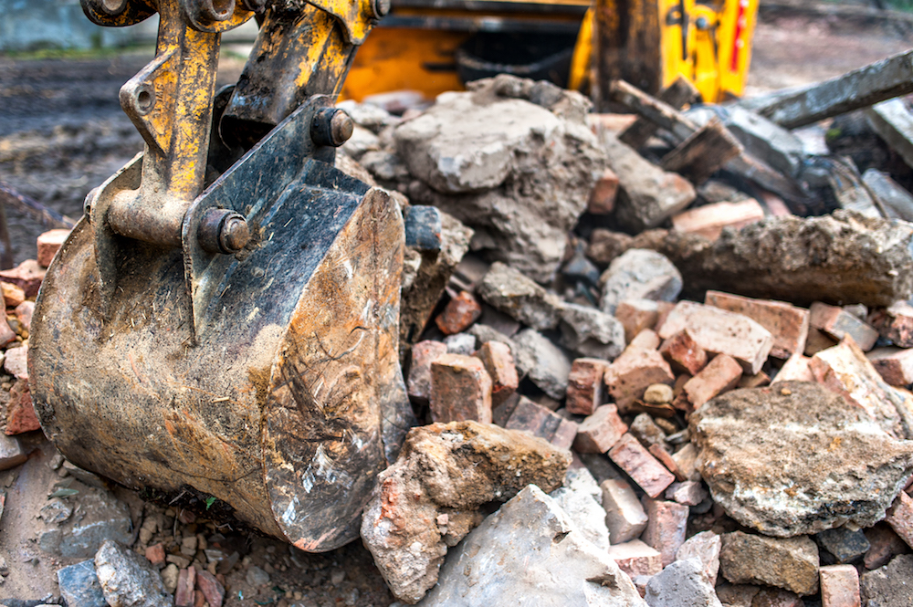 close-up of excavator bucket loading rocks, stones, earth and co