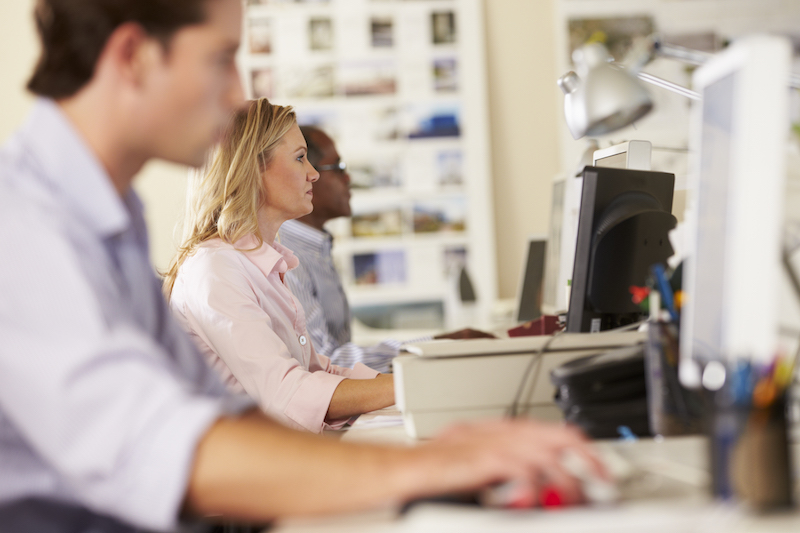 Workers At Desks In Busy Creative Office